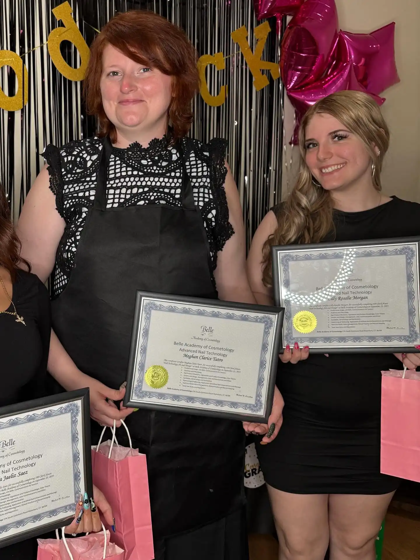 Nail tech graduates with instructor holding certificates
